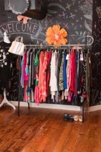 Clothing rack in front of a chalkboard wall with "WELCOME" sign at Mercedes Designer Resale consignment store in Clearwater, FL.