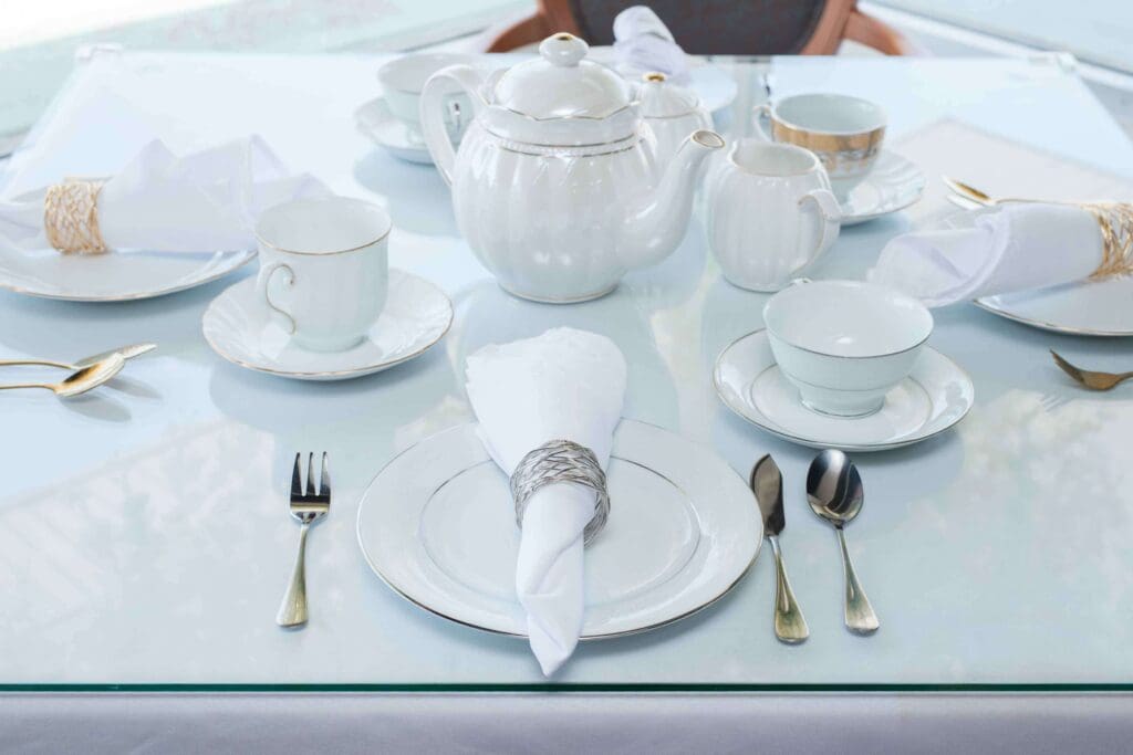 Tea room marketing photos for Kiona's Tea Room. A formal table setting for afternoon tea, with a white teapot, teacups, and elegant silverware on a white tablecloth.